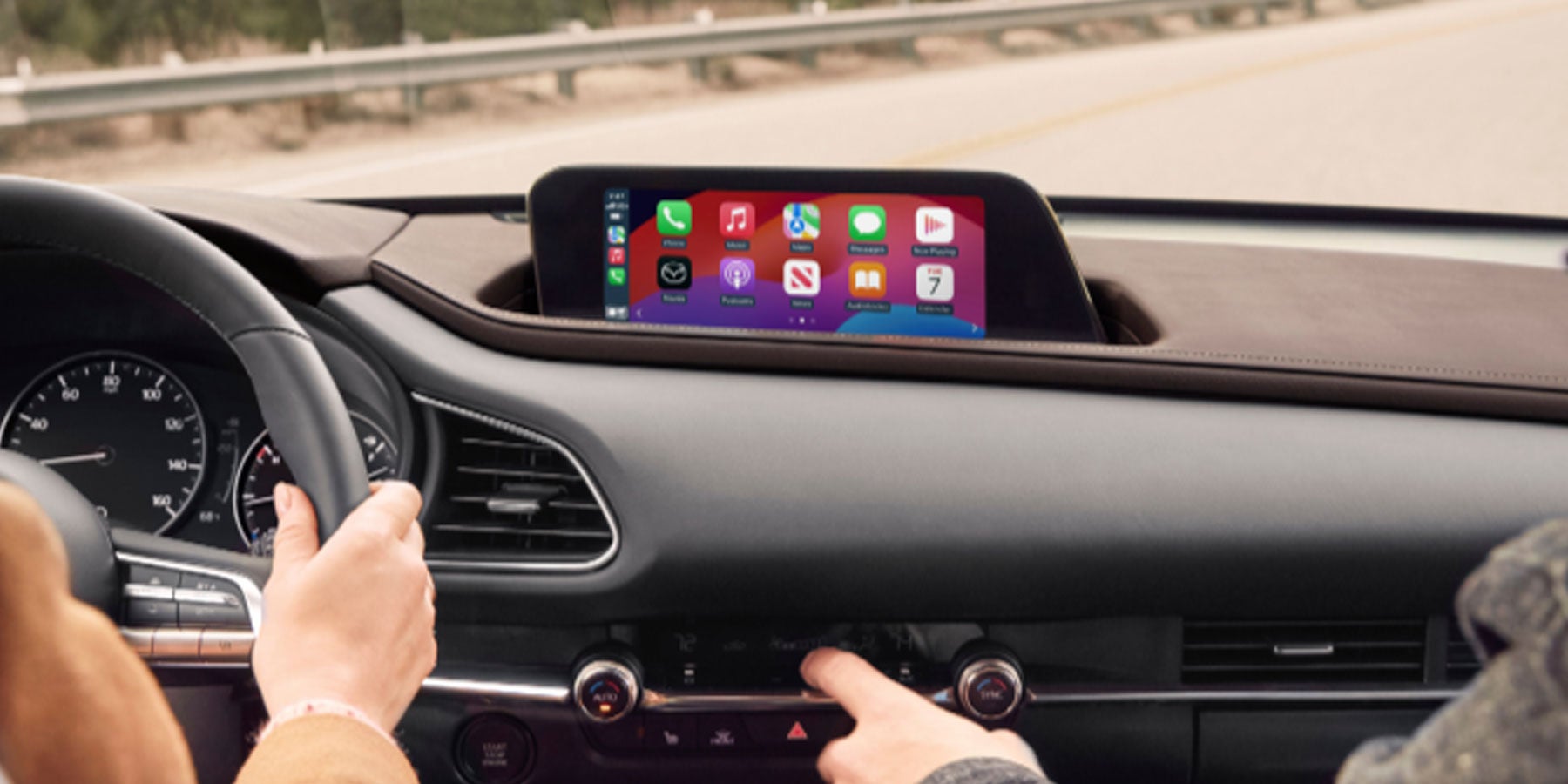 Mazda infotainment display showing Apple CarPlay on the dashboard screen while occupants interact