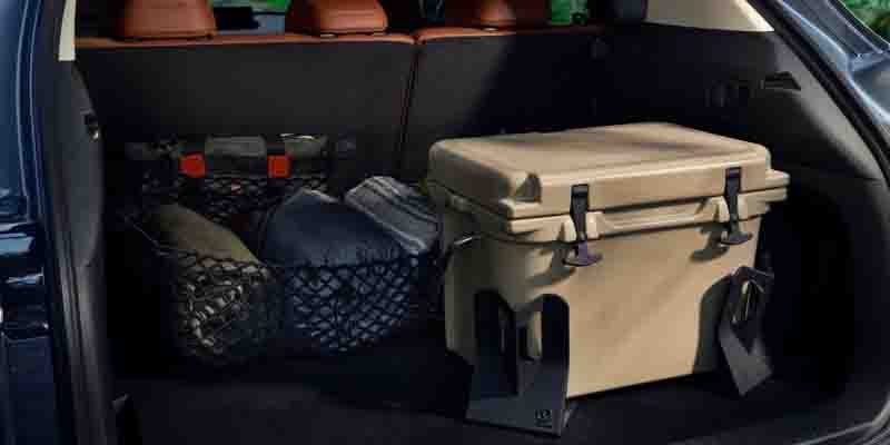 Rear cargo area of a Mazda CX-70 containing a large cooler and secured storage items