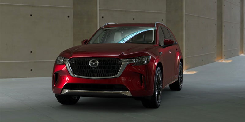 Red Mazda CX-90 SUV driving through a modern indoor corridor
