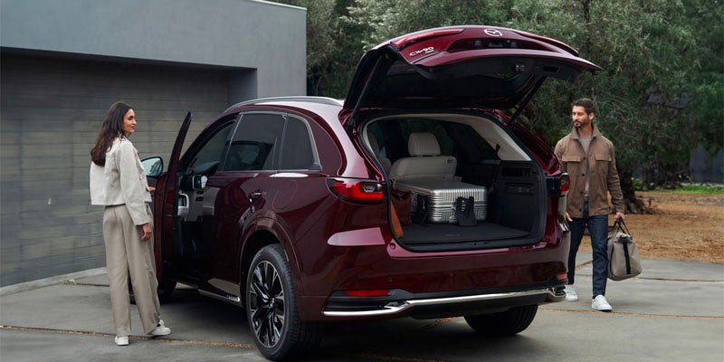 Red Mazda CX-90 SUV parked in a residential driveway with the liftgate open