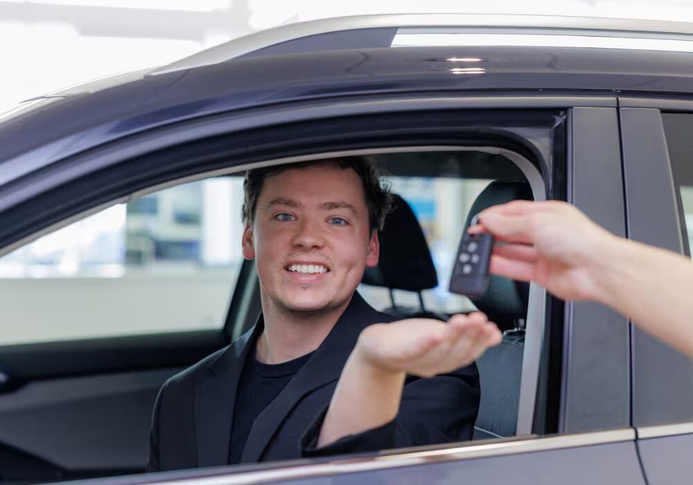 A customer sitting inside of a car at the Flow Mazda of Fayetteville dealership. He is being passed…