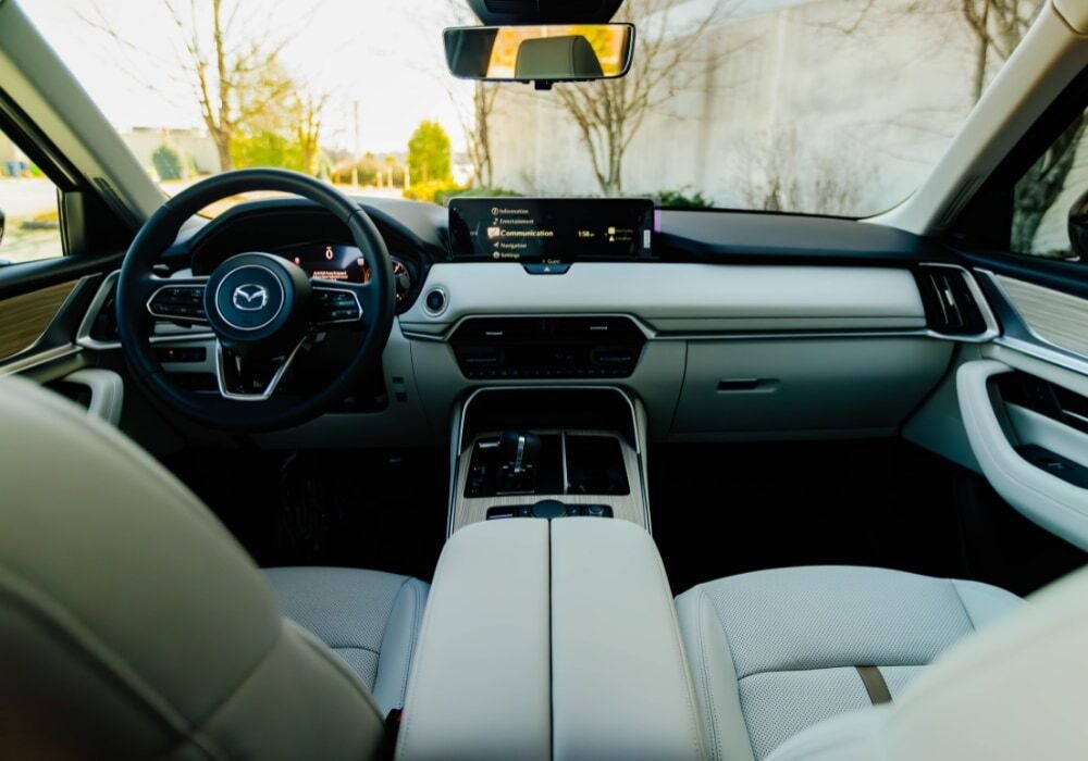 Interior of the 2025 Mazda Cx-90 showing the front dash. The seats are white leather