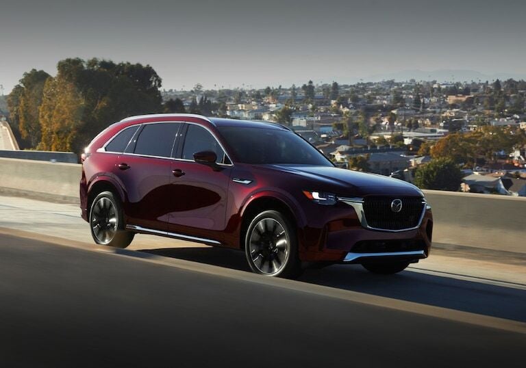 Red 2025 Mazda CX-90 driving on an interstate