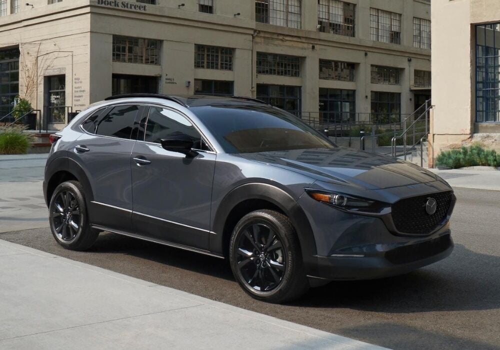Dark Mazda CX-30 SUV parked on a city street with building in the background