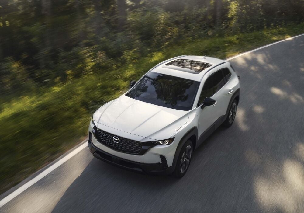 2026 Mazda CX-50 Hybrid driving down the road. The SUV is white and the photo shows it from above