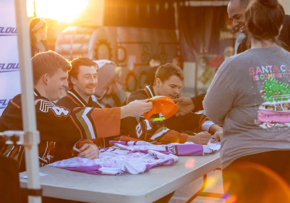 Fayetteville Marksmen Hockey players smile and sign the hats and shirts of fans.