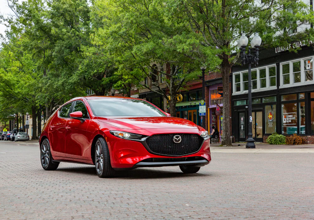 Red Mazda sedan parked in a downtown area